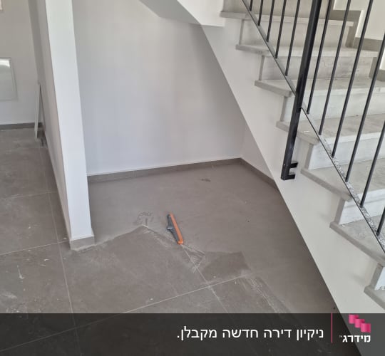 מגב כתום על רצפה מלוכלכת ליד מדרגות